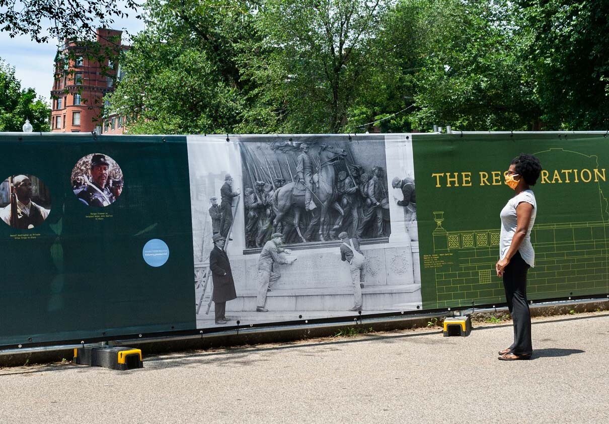 A visitor studies an archival photo of monument restoration